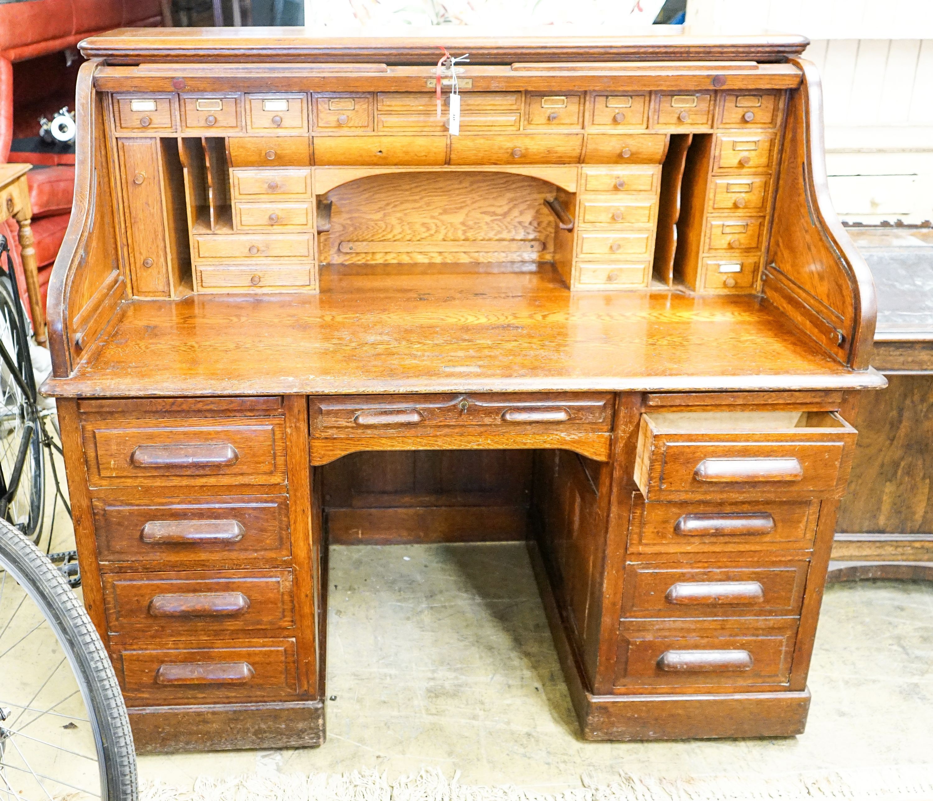 An early 20th century oak roll top desk with 'S' shape tambour, width 140cm, depth 80cm, height 128cm